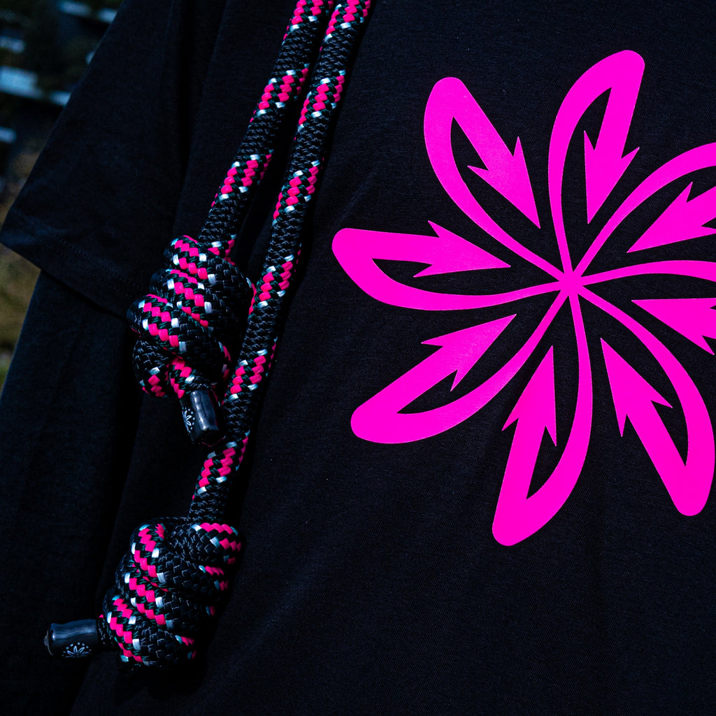 A detail of the hand-made knots of the Good Flow Milano's California rope, showing the magenta and white details against a dark background, next to the magenta logo.
