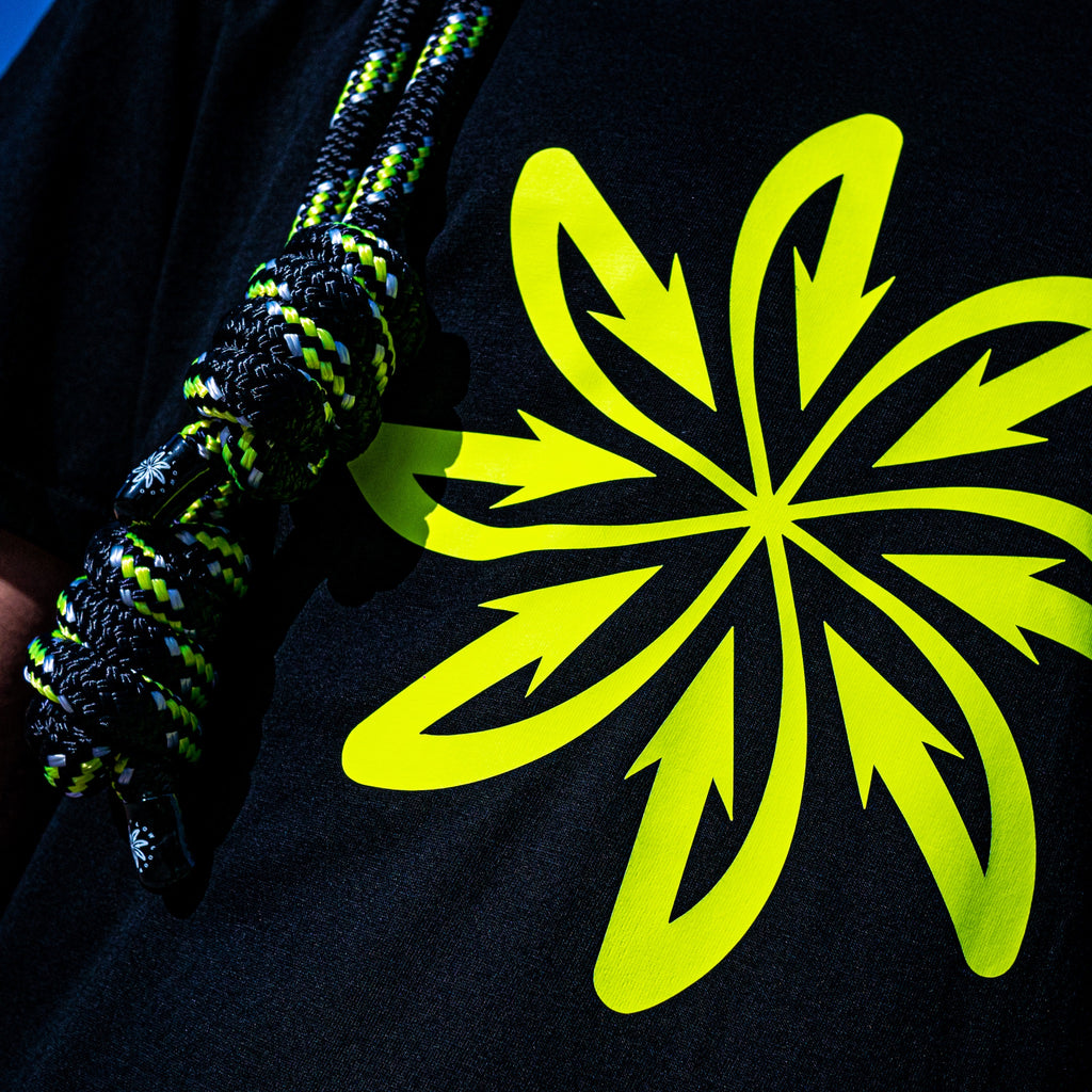 A detail of the hand-made knots of the Good Flow Milano's Court SP rope, showing the yellow fluo and white details against a dark background, next to the yellow fluo logo.